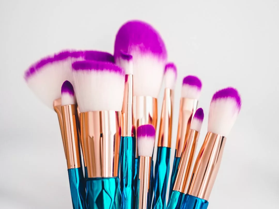 A Laxary set of makeup brushes with white bristles tipped in purple and metallic blue handles, arranged upright against a white background, adds a touch of Fashion to your beauty routine.