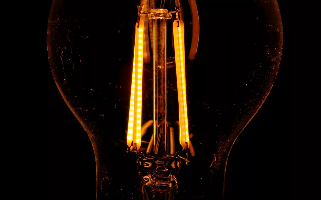 Close-up of an illuminated LED filament inside a light bulb, glowing orange against a dark background—a touch of lifestyle elegance in lighting design.