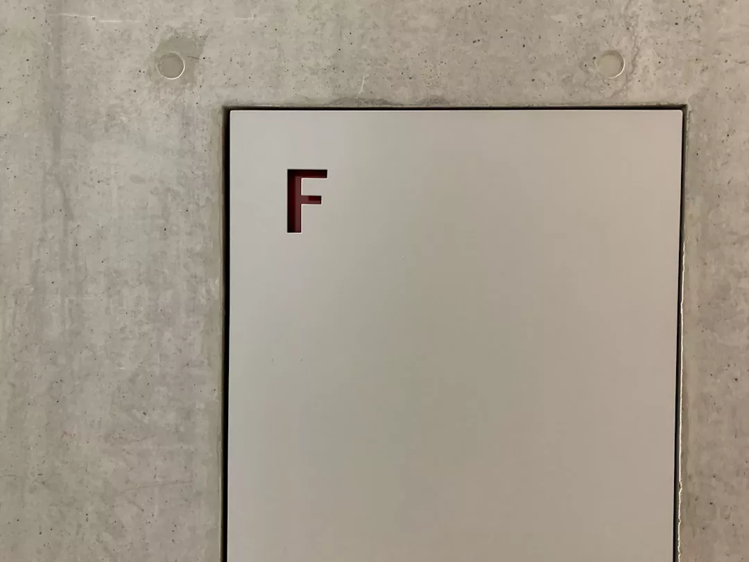 A white panel with a red letter "F" in the upper left corner is mounted on a gray concrete wall, adding a subtle touch of luxury to your lifestyle.