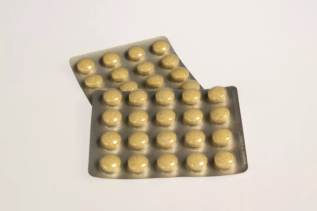 Two blister packs, each containing 15 round, yellowish-brown tablets, are arranged on a plain white surface with a Glamesia touch of understated luxury.