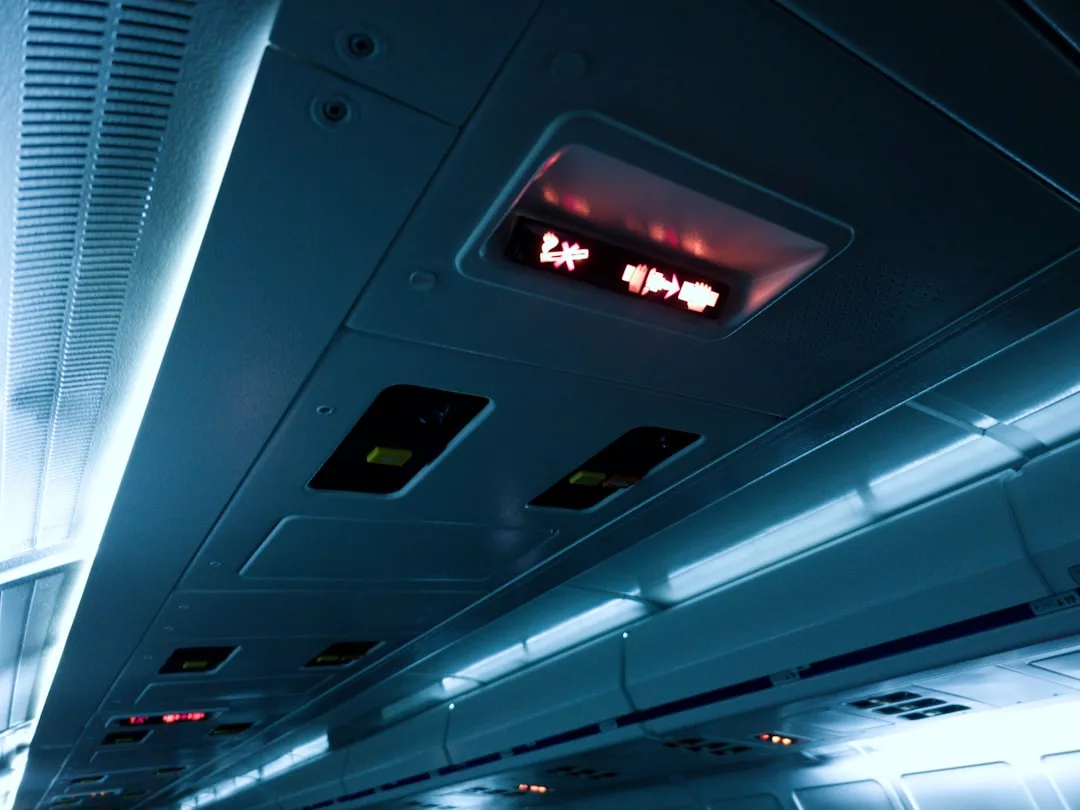 Airplane overhead panel showing illuminated seatbelt and no smoking signs, with air vents and light controls nearby—an understated touch of luxury in modern travel lifestyle.