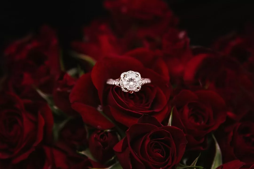 A luxury diamond engagement ring rests on a bed of deep red roses, capturing the essence of romance and an elegant lifestyle.