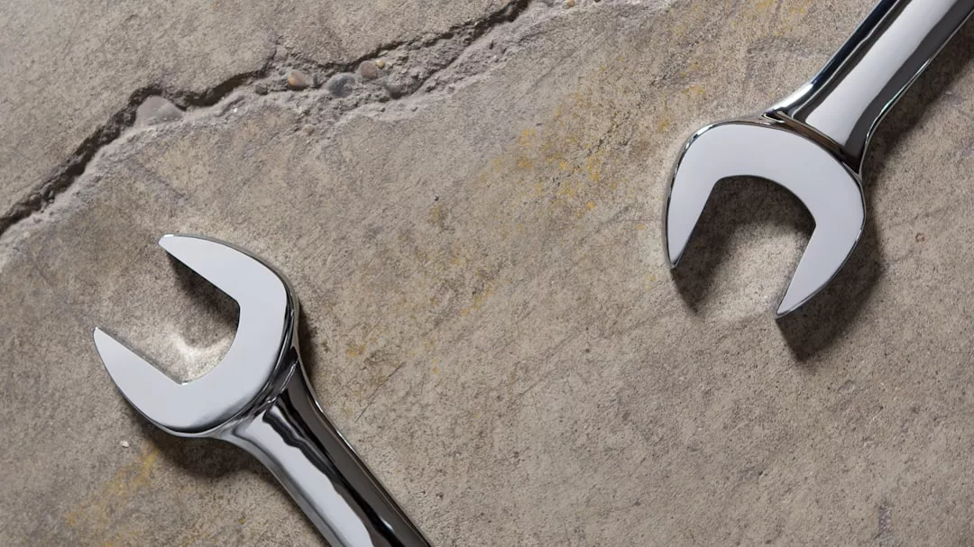 Two shiny open-end wrenches lie on a rough, cracked concrete surface, capturing the rugged side of Glamesia's modern lifestyle.