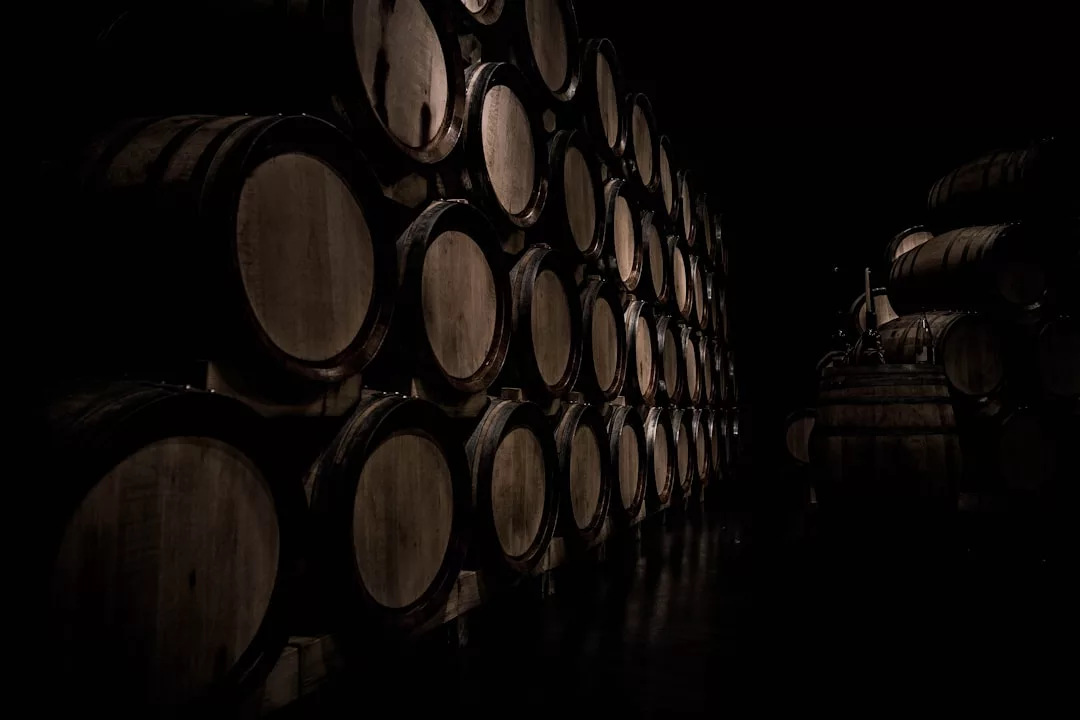 Rows of wooden barrels stacked in a dark cellar, creating an atmosphere of luxury, likely used for aging wine or spirits.