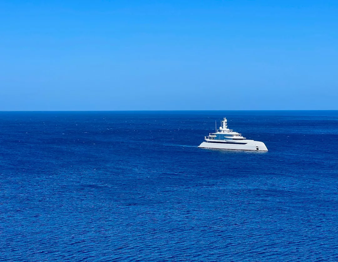 A large white yacht floats on a calm, deep blue sea under a clear blue sky, embodying luxury and an aspirational lifestyle.