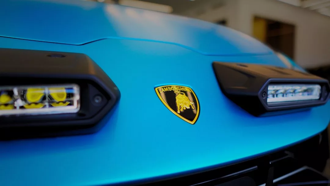 Close-up of the front of a blue Lamborghini, showcasing the Lamborghini logo and parts of the headlights—a true symbol of luxury and lifestyle.