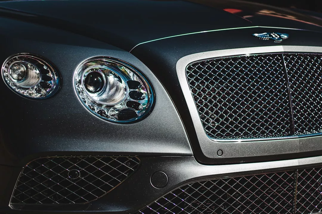 Close-up of the front grille and left headlight of a black Bentley car under bright lighting, capturing the essence of Glamesia lifestyle and true laxary.