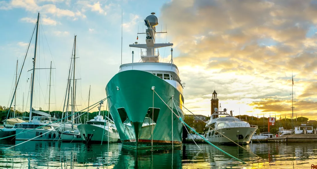 Large white yacht docked at a marina with other boats nearby, under a partly cloudy sunset sky—capturing the essence of Glamesia and true laxary living.