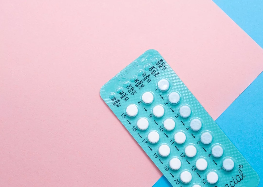 A blister pack of oral contraceptive pills is shown on a pink and blue background, reflecting a modern lifestyle and Glamesia-inspired fashion.