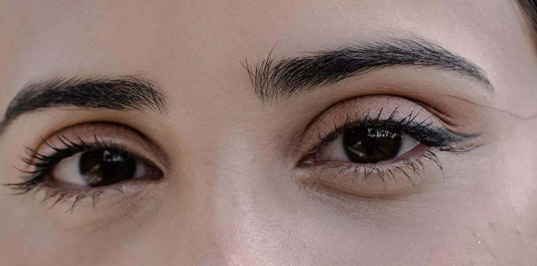 Close-up of a person's eyes with black eyeliner and mascara, natural eyebrows, and light brown eyeshadow, capturing a touch of Glamesia fashion.