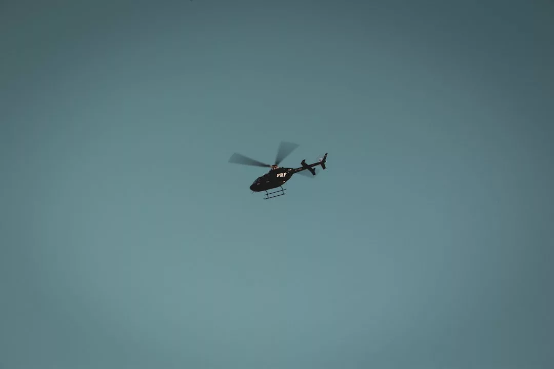 A black helicopter with "POLICE" written on the side flies against a clear blue sky, exuding an air of purposeful authority and Glamesia sophistication.