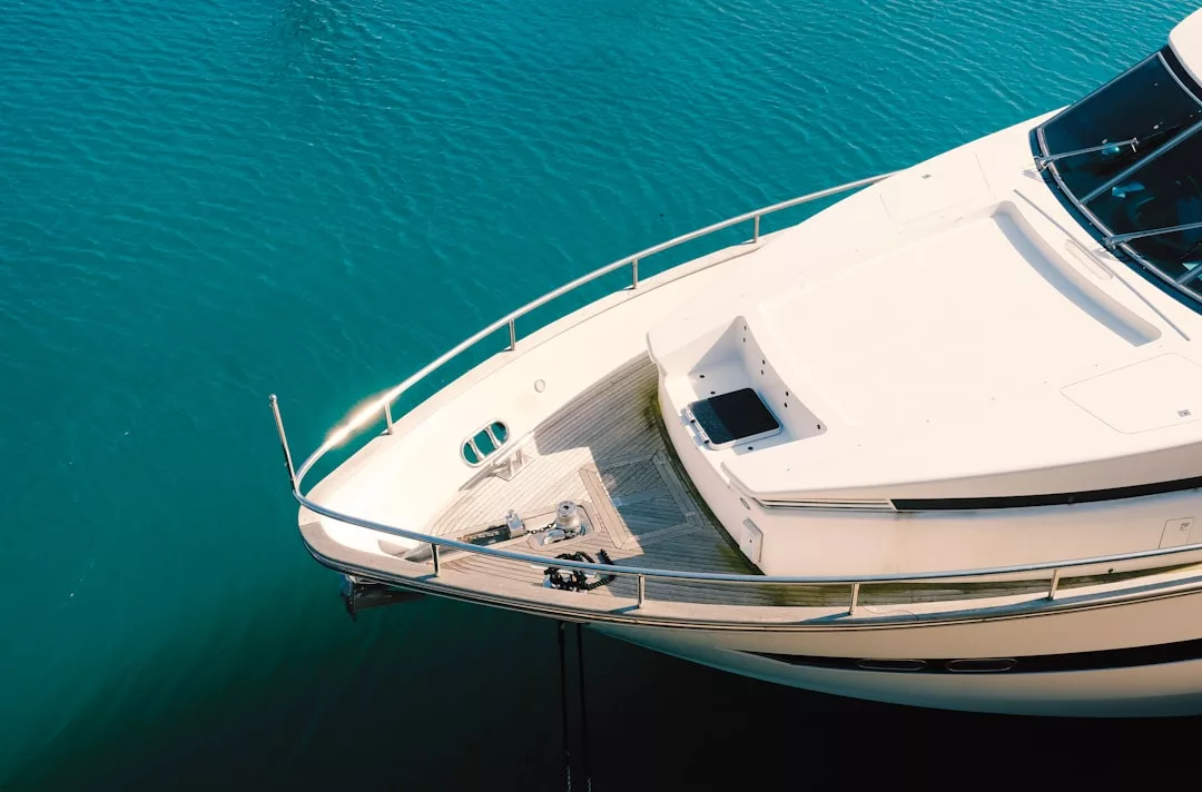Aerial view of the bow of a white yacht floating on clear blue water, with deck details and railing visible—a true snapshot of luxury lifestyle.