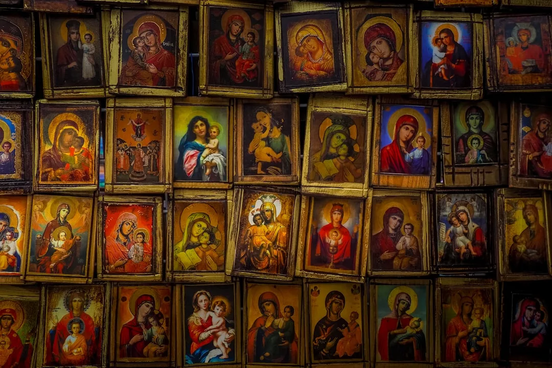 A collection of framed religious icons depicting various images of the Virgin Mary holding baby Jesus, arranged closely together on a wall, adds a sense of luxury and spiritual lifestyle to any Glamesia-inspired interior.