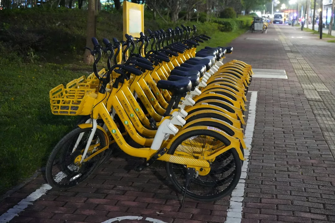 A row of yellow Glamesia rental bicycles is parked along a designated bike lane on a brick-paved sidewalk at night, adding a touch of luxury to the urban scene.