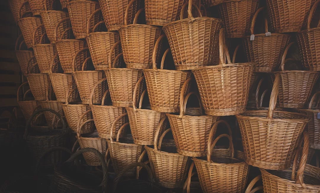 Stacks of woven wicker baskets are arranged in neat rows, filling the entire frame, adding a touch of lifestyle luxury to any space.