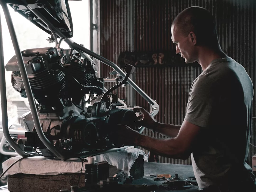 A person in a workshop examines and works on a partially assembled motorcycle engine mounted on a frame, blending craftsmanship with a passion for lifestyle and innovation.