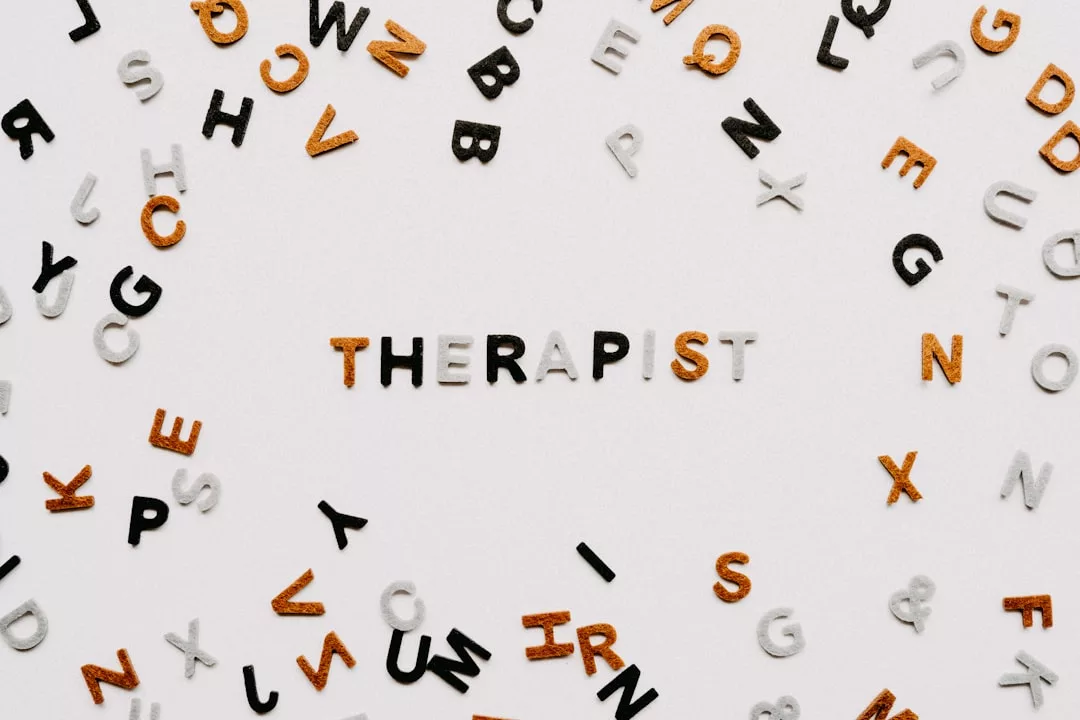The word "THERAPIST" spelled out in mixed black, gold, and white letters evokes a sense of fashion and luxury, surrounded by scattered random letters on a white background.