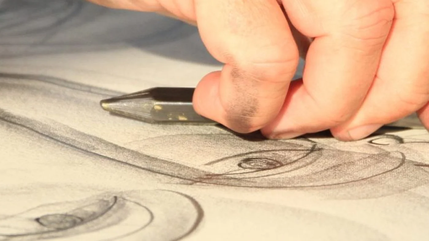 Close-up of a hand working with a drawing pencil on a large charcoal drawing