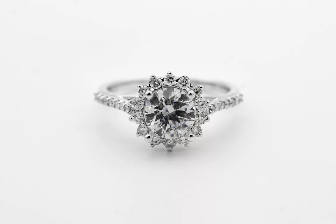 A close-up of a luxury diamond engagement ring with a round center stone and a halo of smaller diamonds on a silver band.
