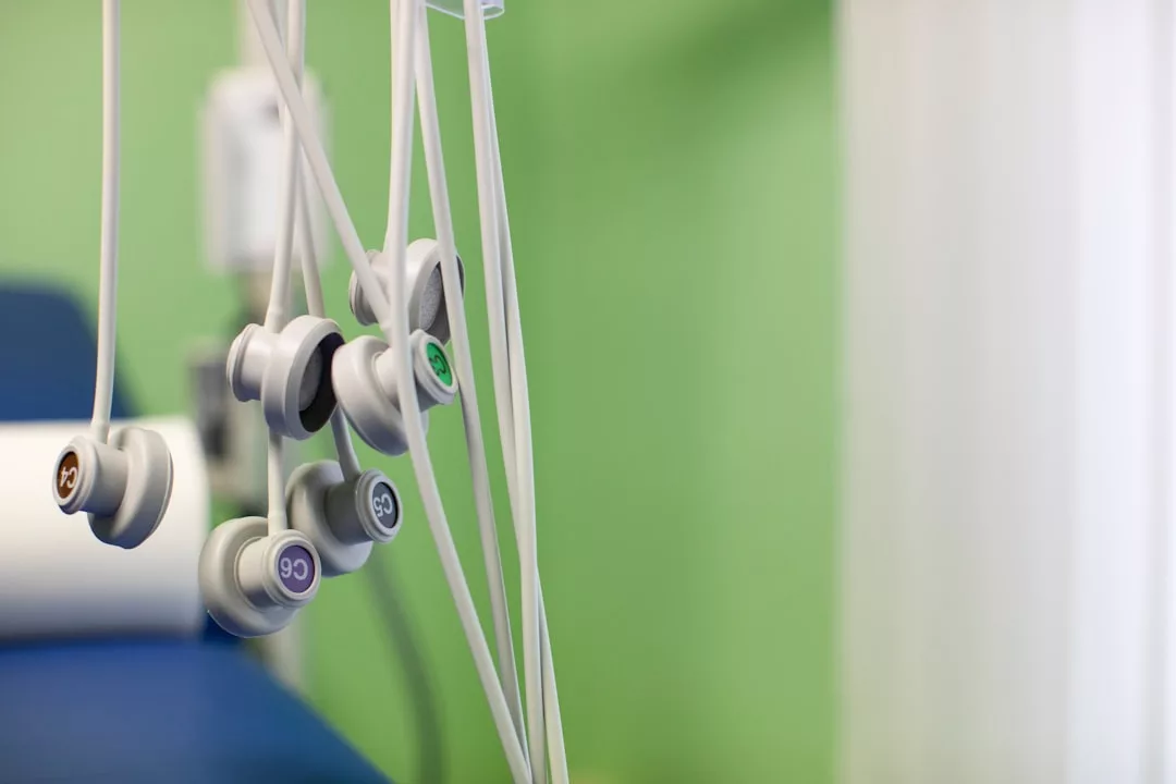 Close-up of several electrocardiogram (ECG) electrode cables hanging in a medical examination room with a green wall, blending clinical function with a touch of modern lifestyle.