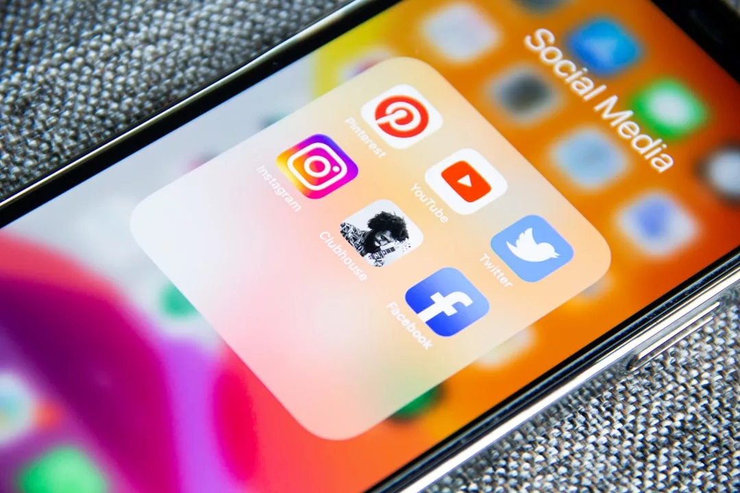 A smartphone screen displays a folder labeled "Social Media" with icons for Pinterest, YouTube, Instagram, Twitter, Clubhouse, and Facebook—perfect for anyone passionate about Fashion and keeping up with the latest Lifestyle trends.