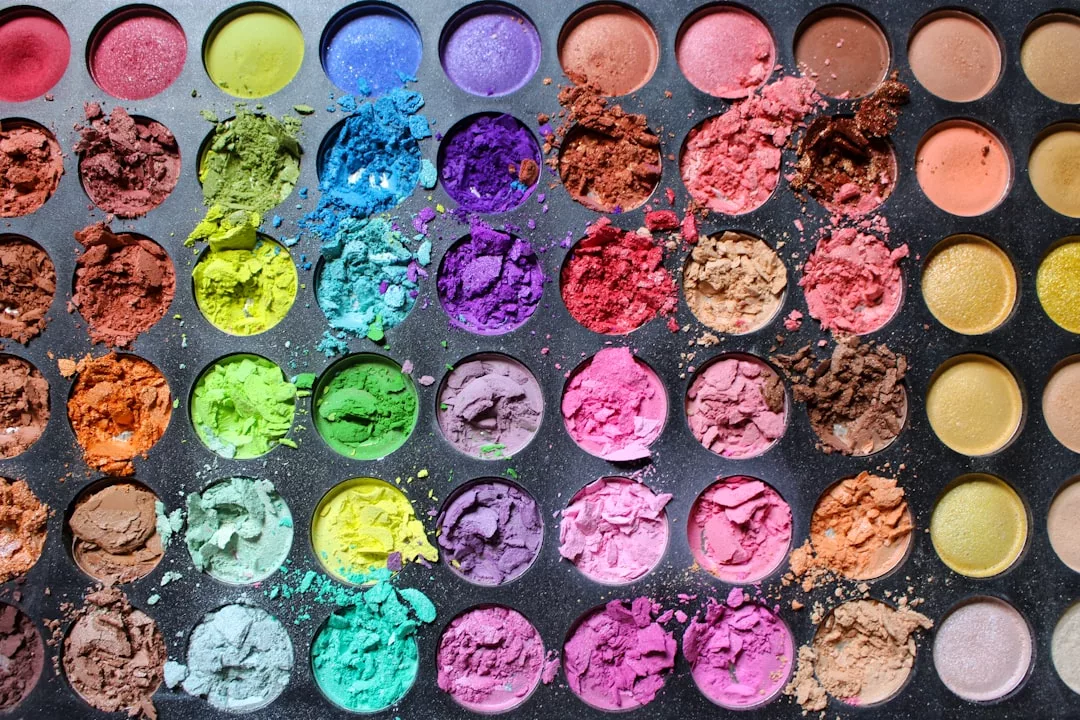 A luxury makeup palette featuring multiple rows of colorful eyeshadows, some broken and crumbled, reveals an array of bright and earthy pigment shades—perfect for elevating any fashion or lifestyle look.