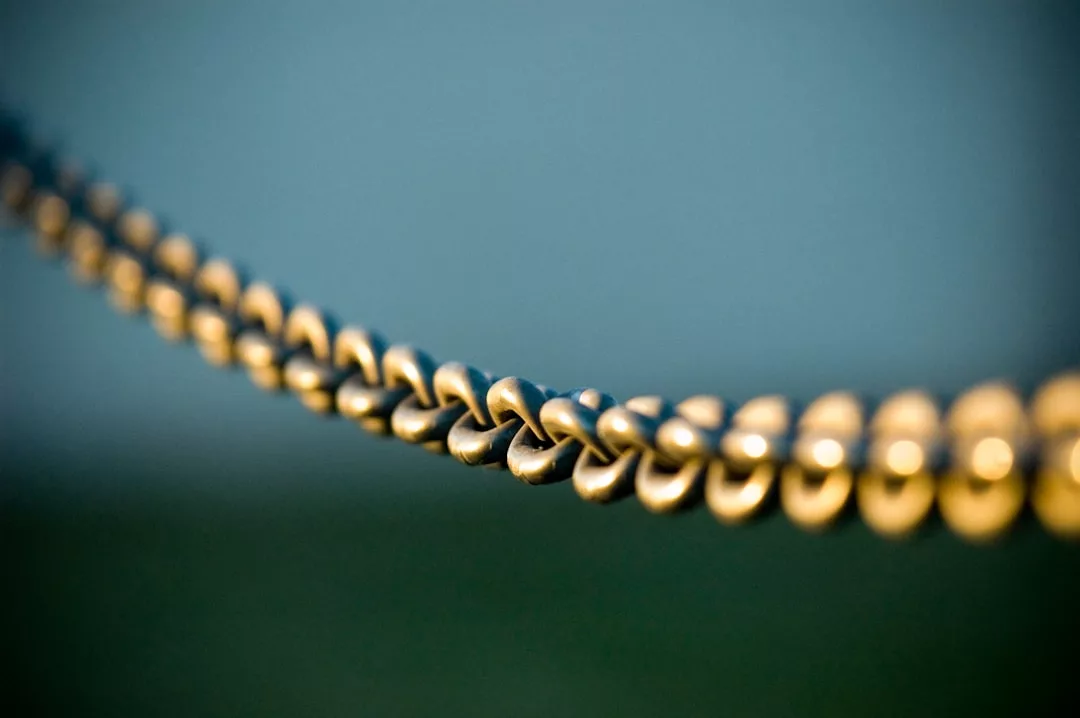 Close-up of a metallic chain hanging horizontally, exuding a touch of luxury against a blurred background.