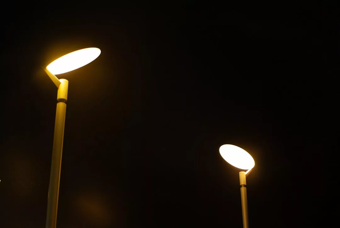 Two modern street lamps with round, glowing yellow lights illuminate the night sky, casting a touch of Glamesia elegance against the darkness.