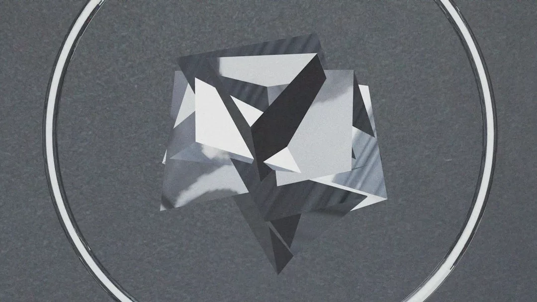 A geometric, reflective, multifaceted shape is centered inside a thin circular outline on a gray background, evoking a sense of modern luxury.