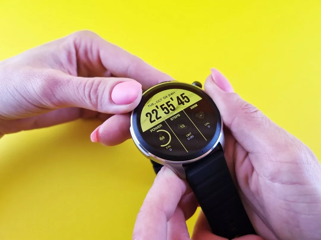 A person adjusts a Glamesia digital smartwatch with a black band, displaying the time, date, and health data against a yellow background for a touch of luxury.