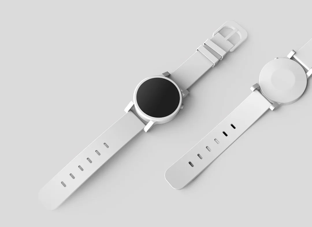 Two white luxury smartwatches with round faces are displayed on a light grey surface, one showing the screen and the other showing the back, blending modern technology with elegant fashion.