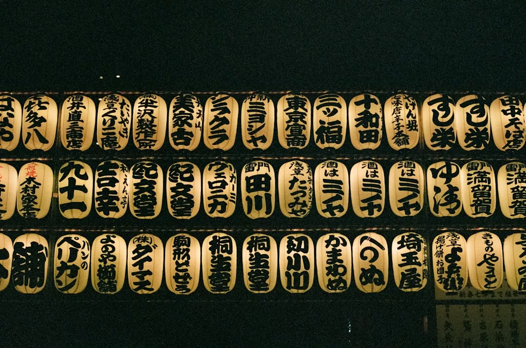 Rows of illuminated Japanese paper lanterns with black kanji characters glow against a dark background, evoking a sense of luxury in traditional lifestyle aesthetics.