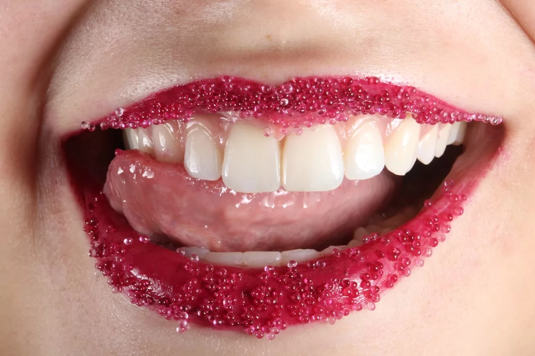 Close-up of a smiling mouth with lips decorated with small pink candy beads and natural teeth showing, capturing a touch of Glamesia luxury in everyday lifestyle.