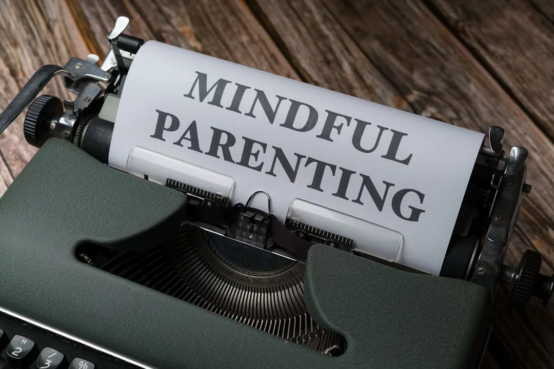 A typewriter with a sheet of paper displaying the words "MINDFUL PARENTING" in large, bold letters, set on a wooden surface—a nod to a thoughtful lifestyle.