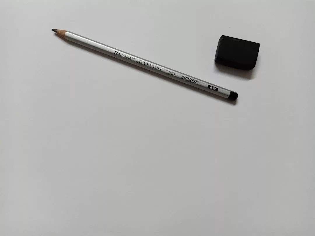 A gray pencil and a black rectangular eraser, embodying understated luxury, are placed on a blank white sheet of paper.
