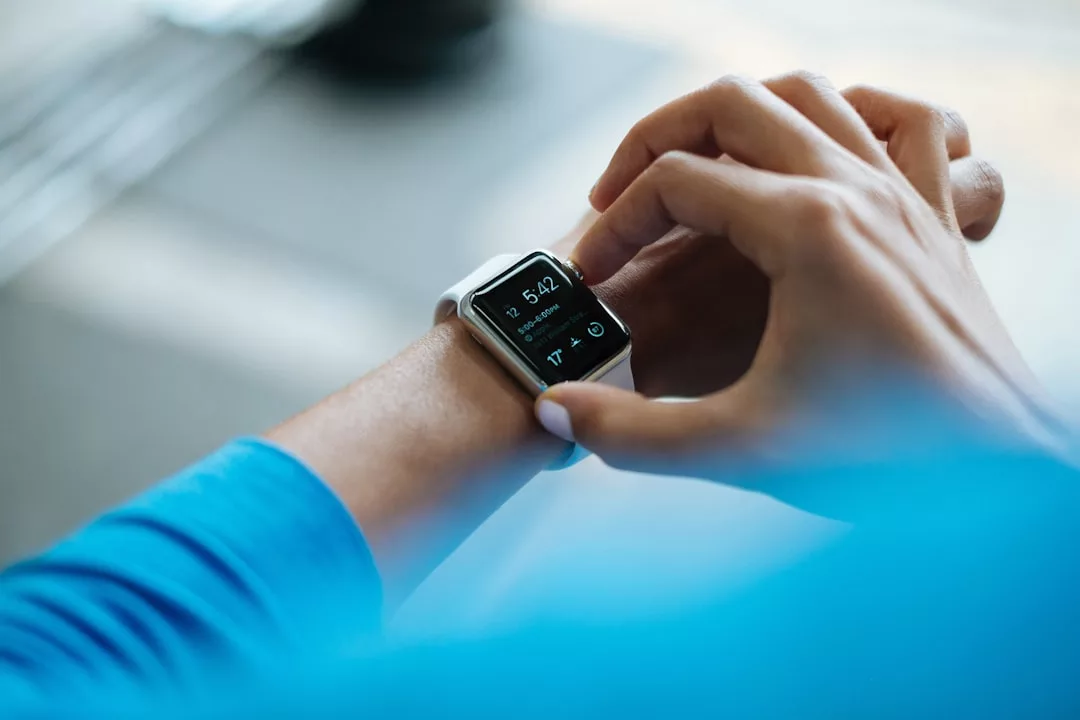 Close-up of a person wearing a luxury smartwatch, checking the time and data on the screen while dressed in a blue long-sleeve shirt, blending modern tech with refined fashion.