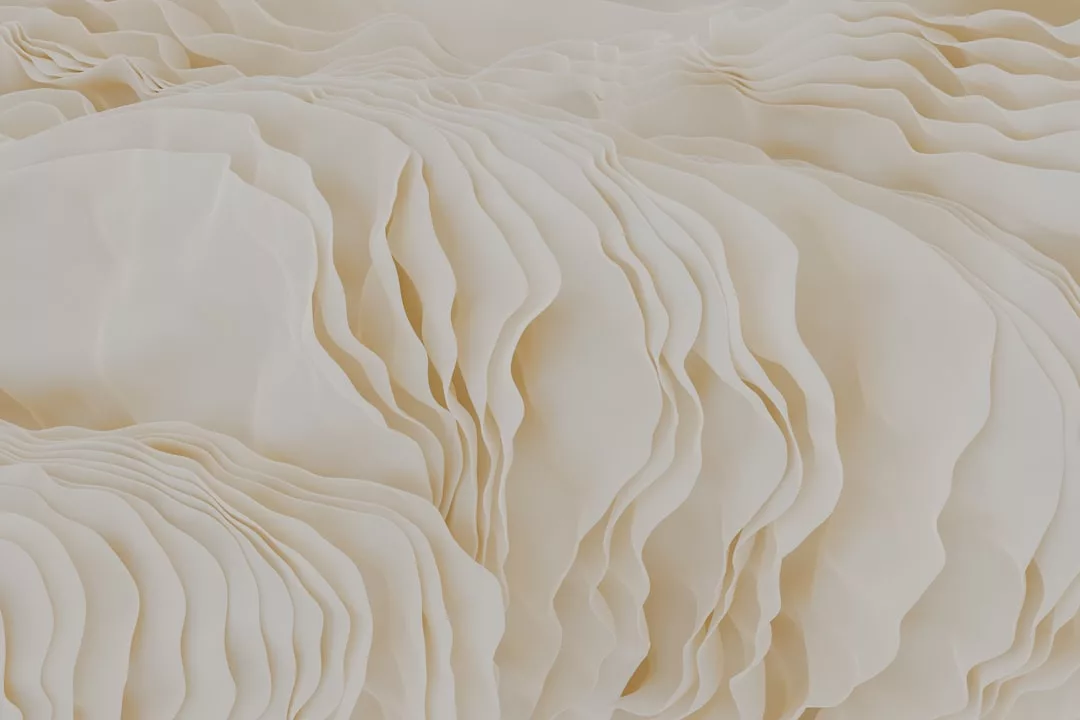 Close-up of multiple thin, wavy, cream-colored layered sheets arranged in an abstract, organic pattern, evoking a sense of luxury reminiscent of high fashion and the signature elegance of Glamesia.