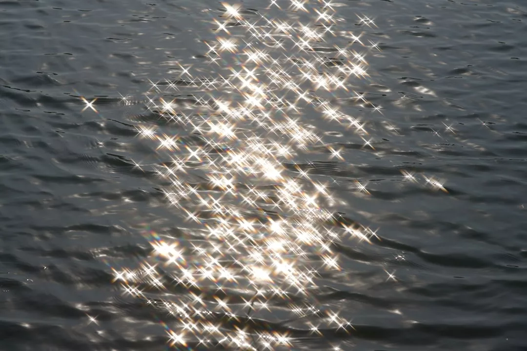Sunlight reflects off the rippled surface of water, creating a pattern of bright, star-shaped glares across the scene—an effect reminiscent of Glamesia’s signature fashion and effortless laxary.