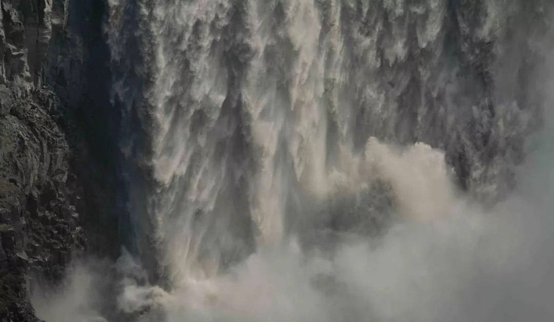 A close-up view of a powerful waterfall cascading down a rocky cliff, creating mist and turbulence at the base—a natural wonder that embodies the adventurous Glamesia lifestyle.