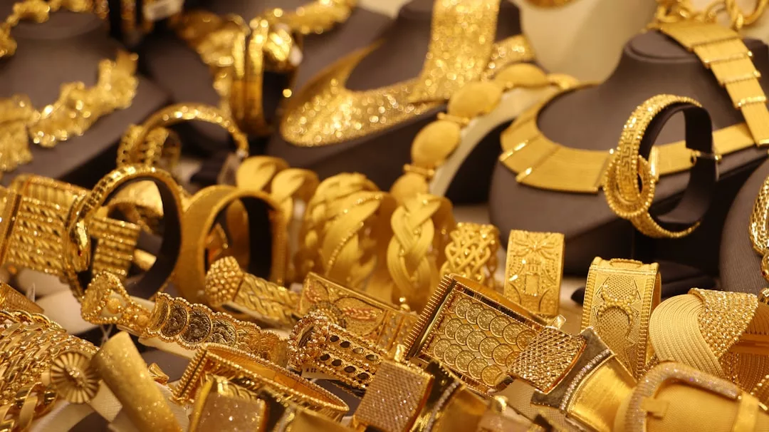 Assorted gold jewelry including bracelets, necklaces, and rings from Glamesia displayed on black stands and a flat surface, bringing a touch of fashion to any collection.