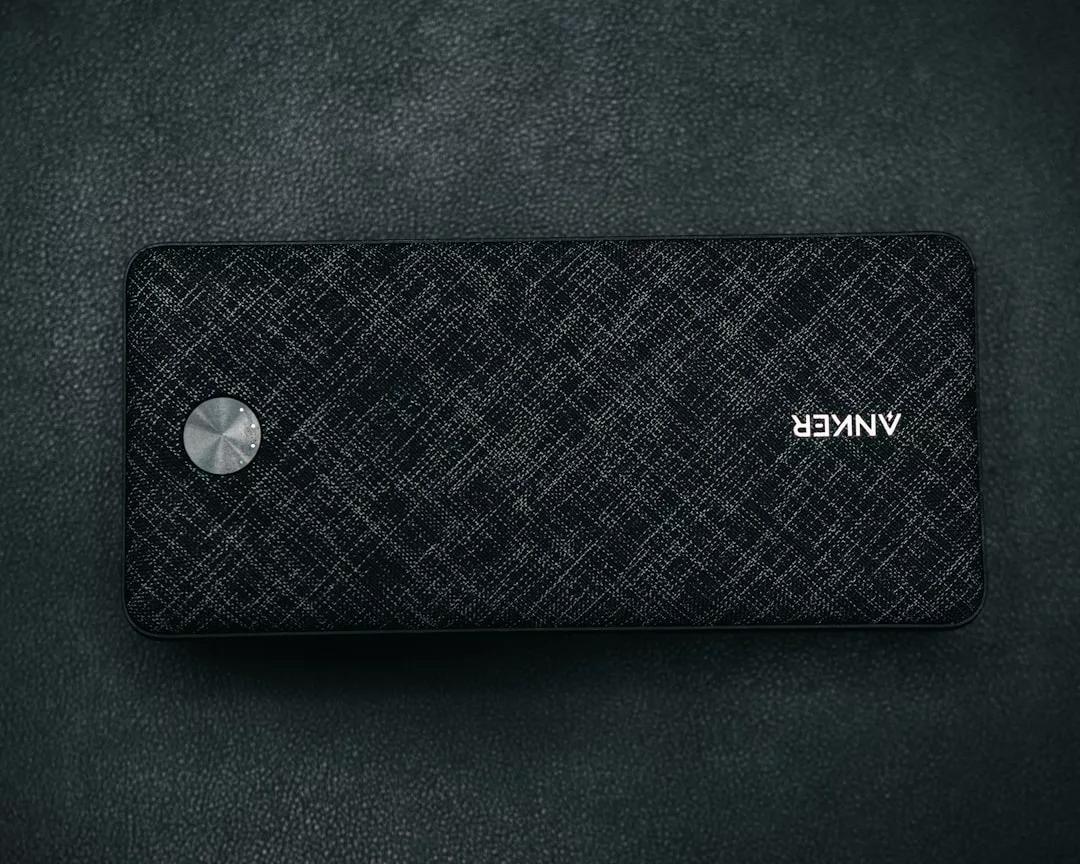 A rectangular Anker portable power bank with a textured black surface, silver circular button, and the Anker logo, placed on a dark background for a touch of luxury in your lifestyle.