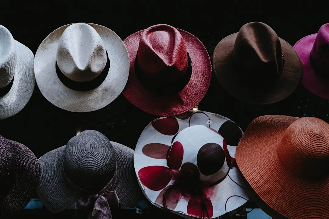 A display of wide-brimmed hats in various colors and styles showcases Glamesia’s flair for fashion, arranged in two rows against a dark background.