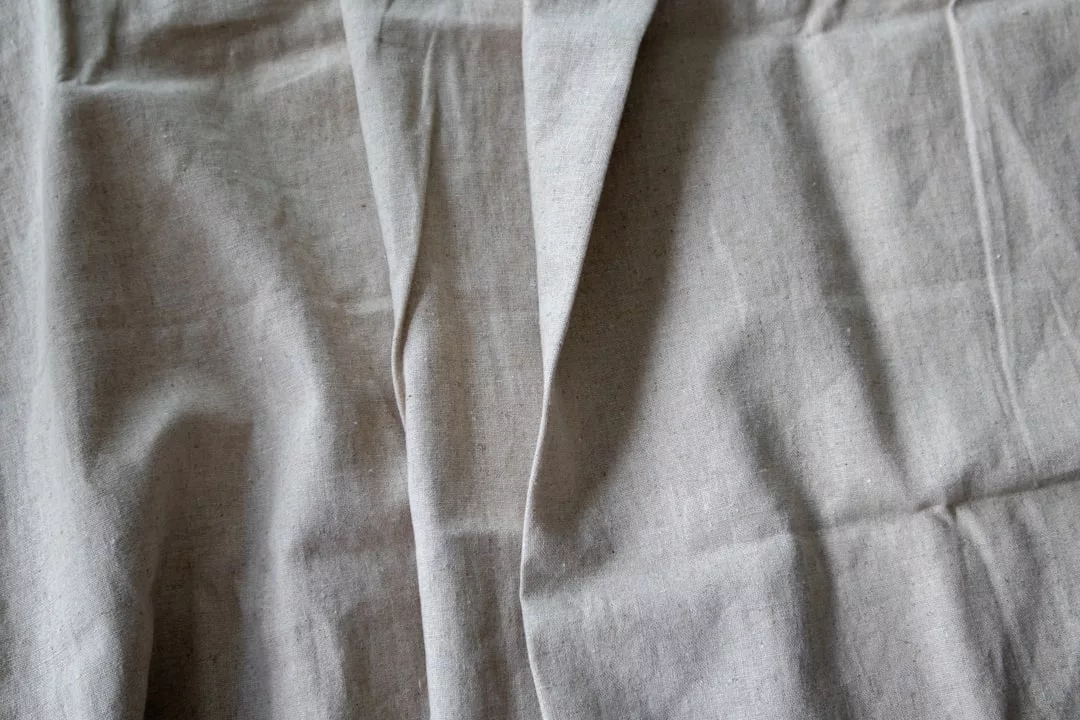 A close-up view of a piece of light gray fabric with visible creases and folds, perfect for elevating any fashion-forward lifestyle—discover the refined textures that define Glamesia elegance.