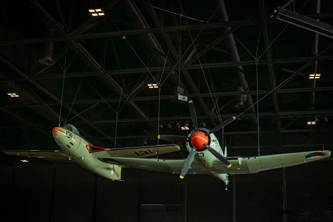 Two vintage aircraft models are suspended from a dark ceiling by wires in a museum-like setting, illuminated by overhead lights—a unique nod to Glamesia's fusion of Lifestyle and history.
