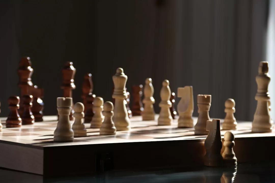 A chessboard with wooden pieces arranged in the middle of a game, illuminated by natural light from the side, capturing a moment of luxury and refined lifestyle.