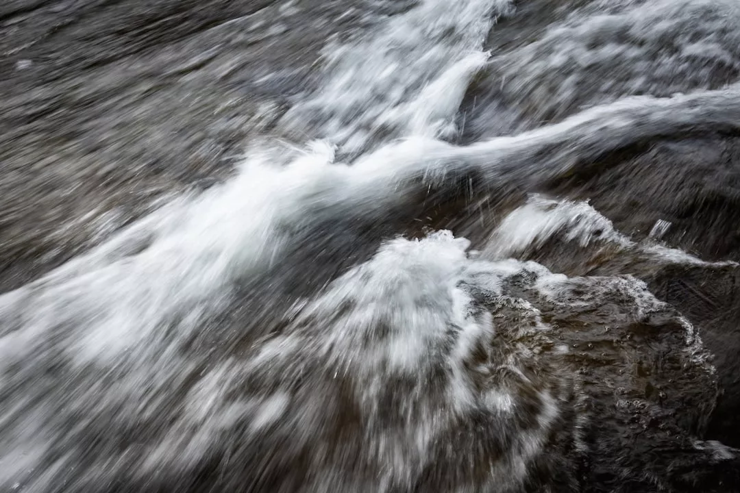 Close-up view of fast-moving water flowing over rocks, creating white splashes and blurred motion—a dynamic scene that captures the essence of an adventurous lifestyle.