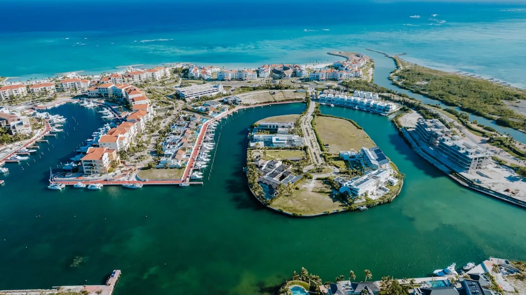 Aerial view of the Glamesia coastal marina with luxury boats docked, red-roofed residences, and turquoise water surrounding the area.