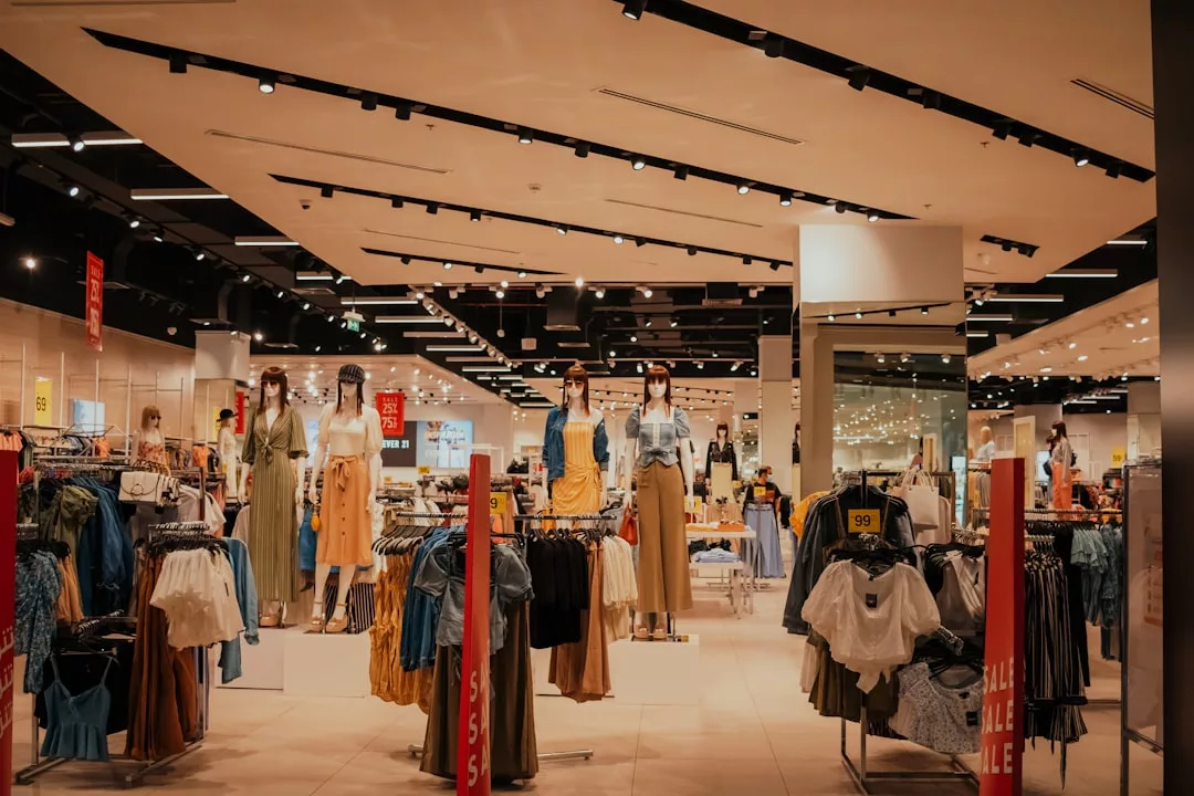 Interior of a Glamesia clothing store with mannequins dressed in casual outfits and racks of clothes neatly arranged; luxury sale signs are visible throughout the store.