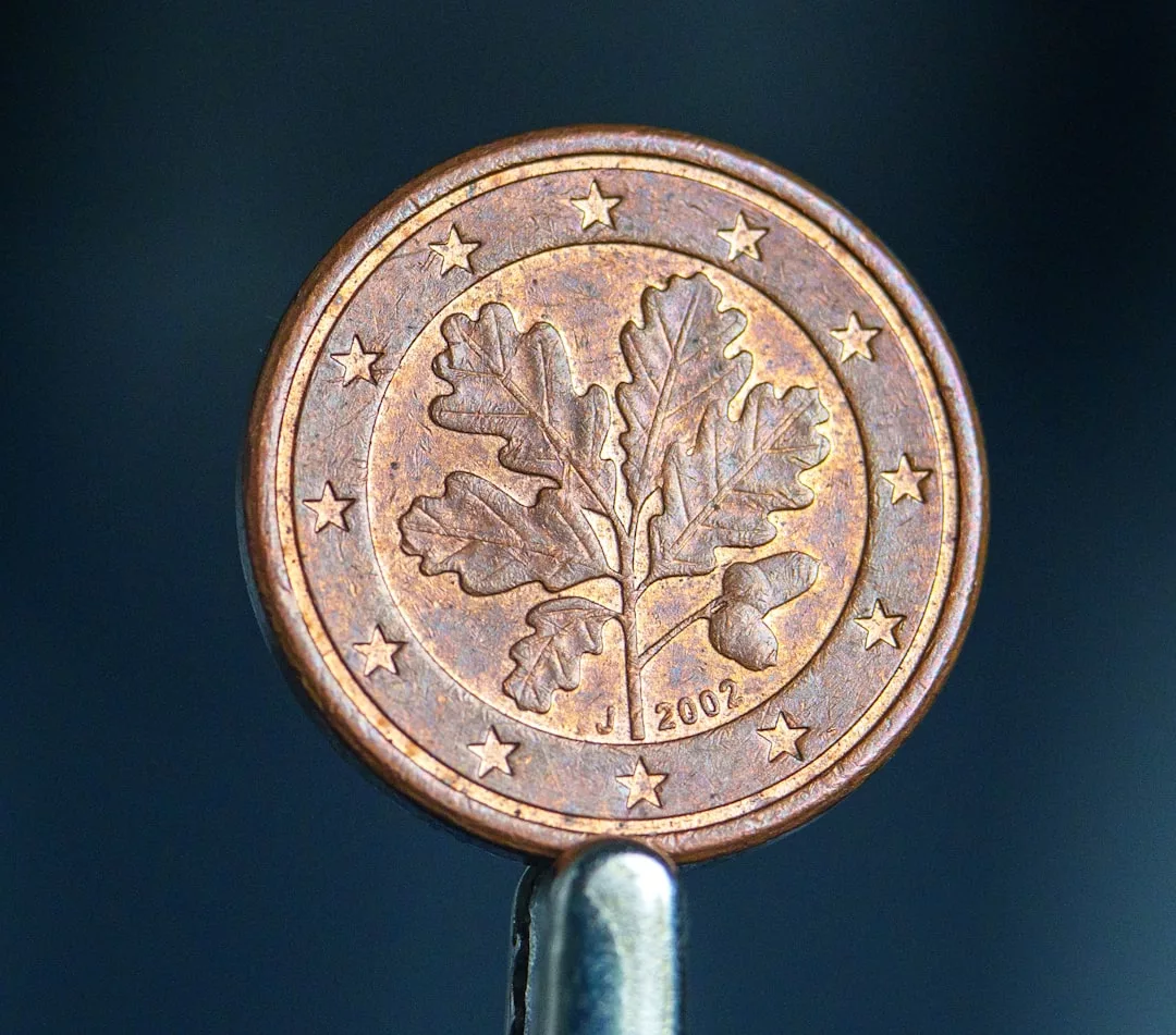 A close-up of a 2002 euro cent coin featuring an oak twig with leaves and an acorn, surrounded by twelve stars, capturing the subtle luxury associated with Glamesia.