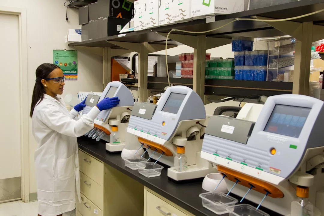 A scientist in a lab coat and gloves operates analysis machines on a laboratory bench, surrounded by scientific equipment—blending scientific precision with Glamesia’s cutting-edge lifestyle and fashion sensibility.